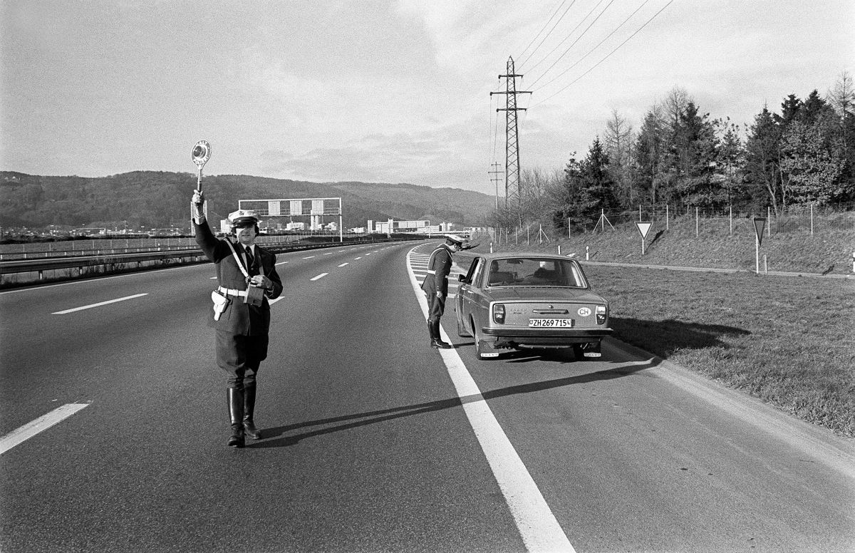 1605762 –  Eine Polizeipatrouille kontrolliert ein Auto an einem der autofreien Sonntage im November / Dezember 1973 in der Schweiz. Foto: KEYSTONE